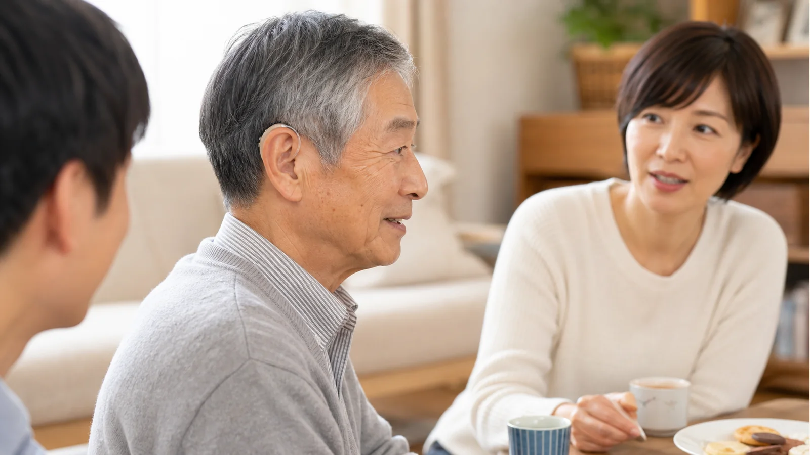 目立たない集音器をつけて家族と会話する高齢者